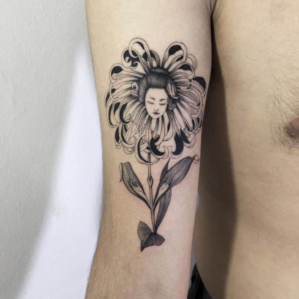 Black ink tattoo of a Geisha’s serene face emerging from a flower, blending delicate botanical elements with traditional Japanese aesthetics.