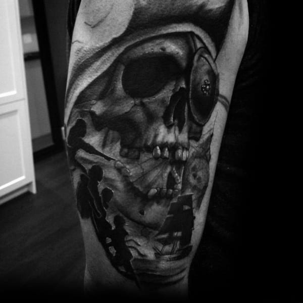 Black and gray tattoo of One-Eyed Willy from The Goonies featuring a skull with an eye patch, silhouettes of the kids, and a pirate ship.