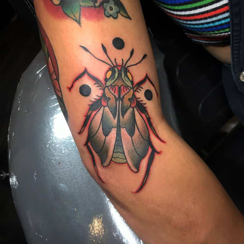 Bold cicada tattoo on the forearm, featuring vibrant colors, red accents, and black geometric elements for a modern design