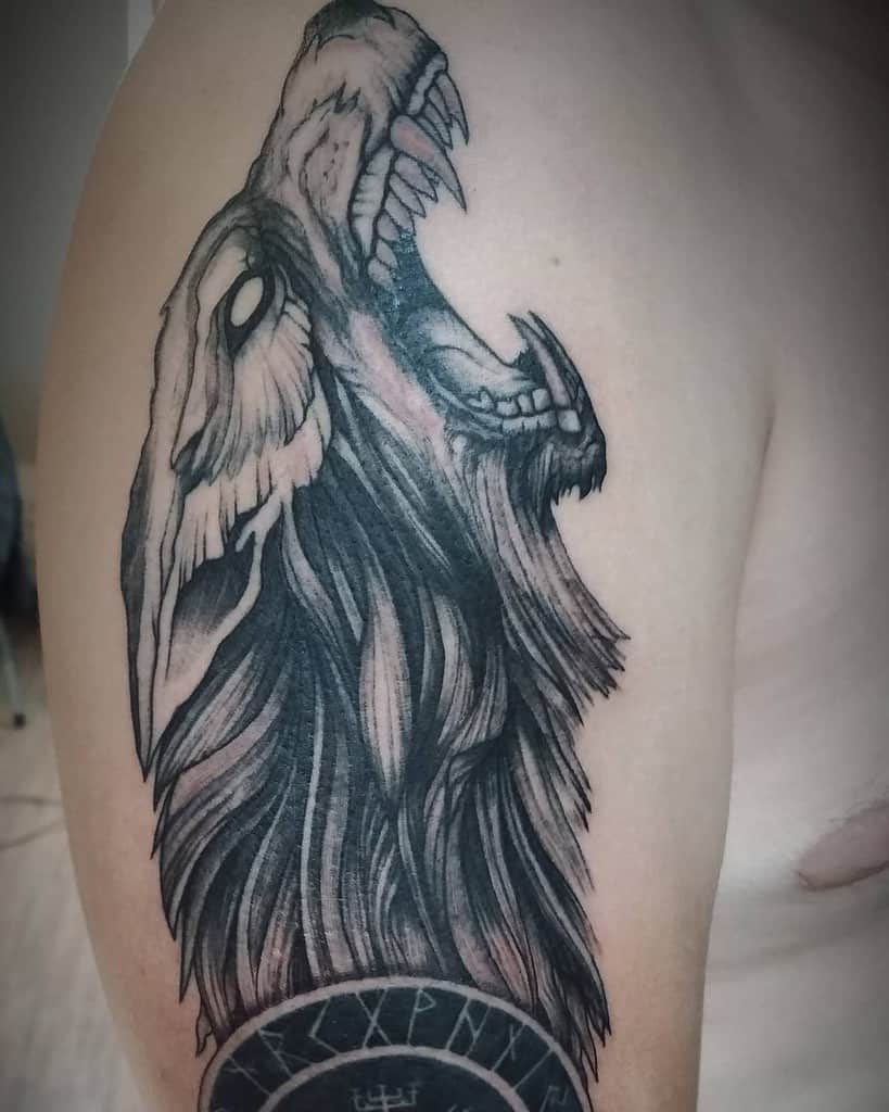 Upper arm tattoo of Fenrir howling, with striking details and runic symbols below, inspired by Norse mythology