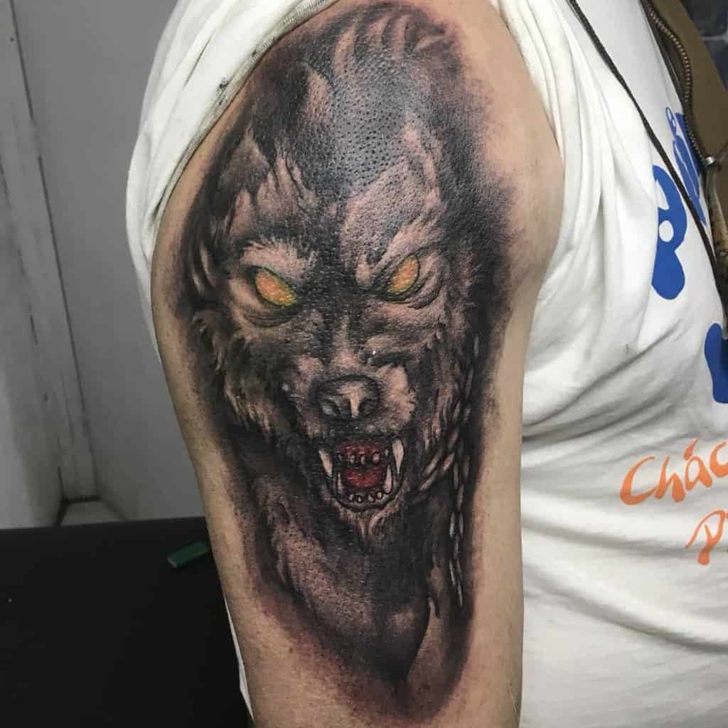 Upper arm tattoo of Fenrir with glowing yellow eyes and fierce details, capturing the wolf's menacing presence from Norse mythology