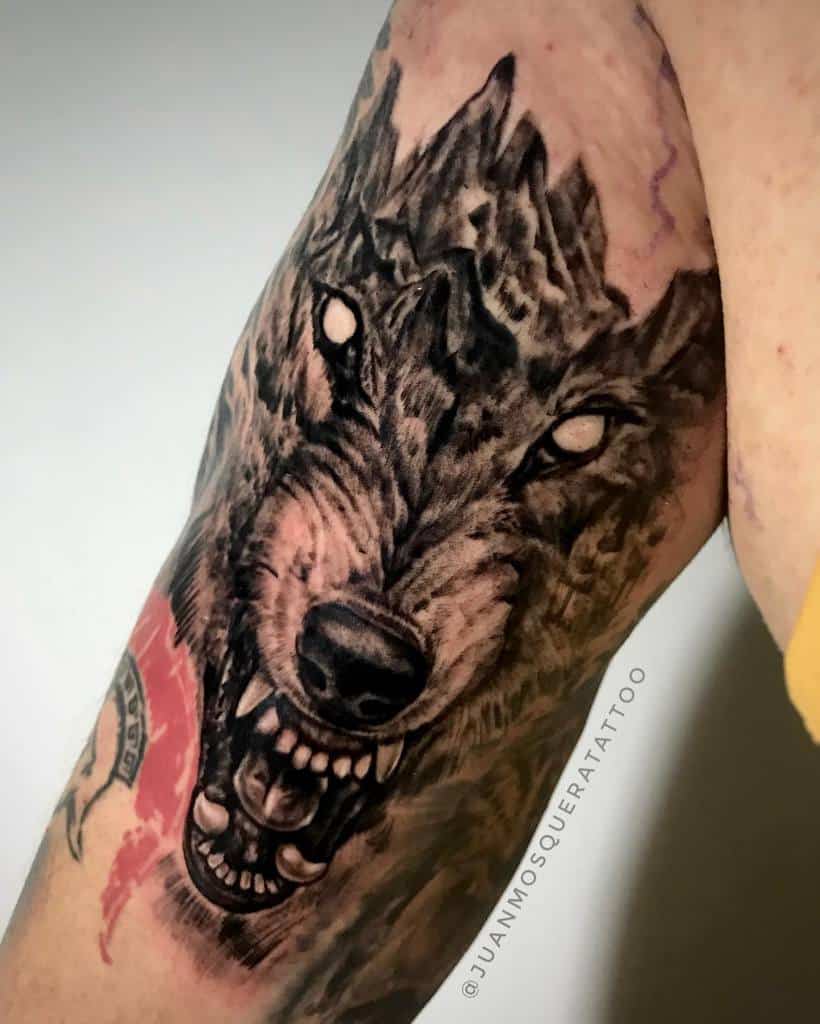 Detailed upper arm tattoo of Fenrir with piercing white eyes and fierce teeth, symbolizing the mythical Norse wolf