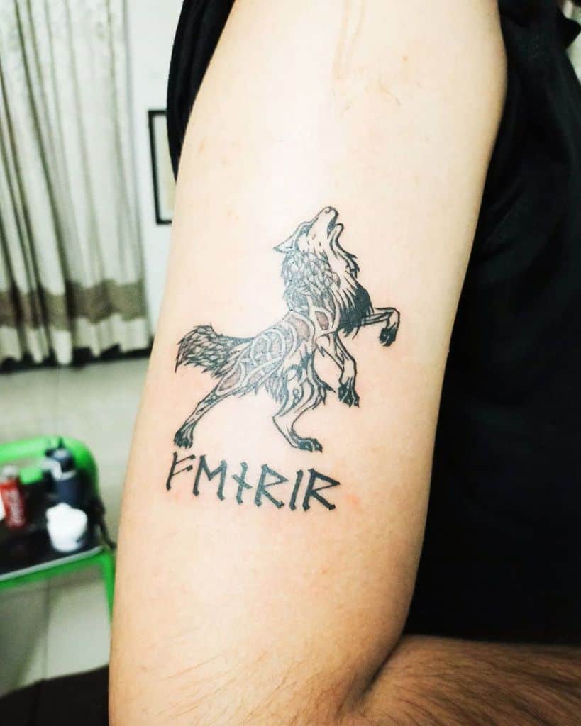 Minimalist arm tattoo of Fenrir howling, accompanied by runic-style lettering spelling 'FENRIR,' inspired by Norse mythology