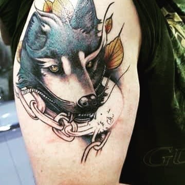 Vivid Norse wolf tattoo with autumn leaves and chains, symbolizing strength, transformation, and resilience