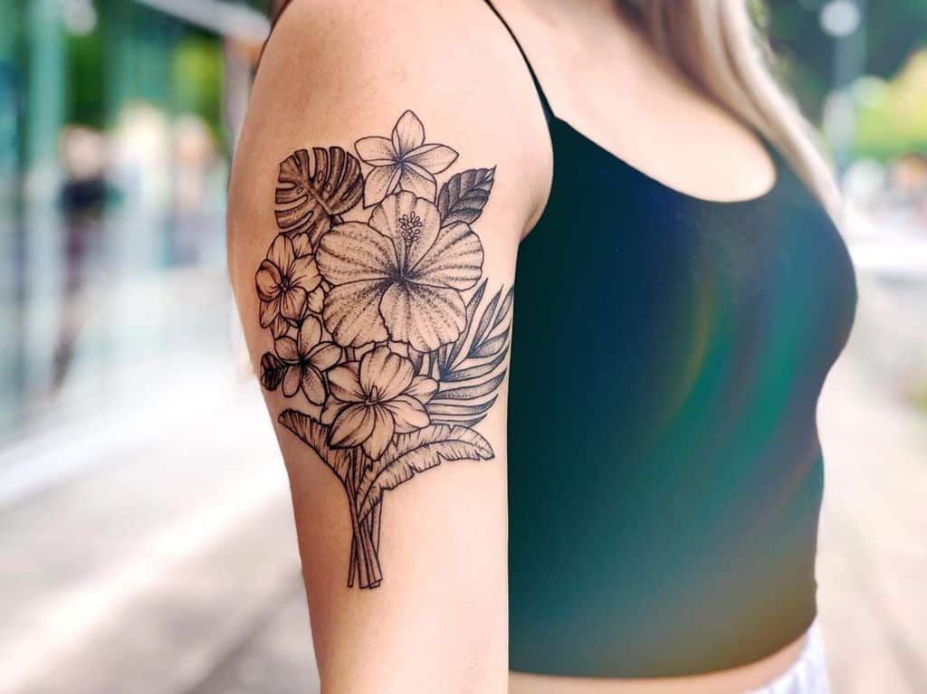 Arm tattoo of tropical flowers, including hibiscus and plumeria