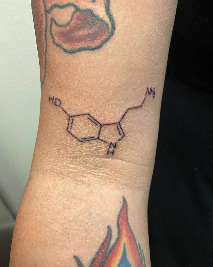 A tattoo of the serotonin molecule elegantly graces a person's arm, symbolizing balance and happiness
