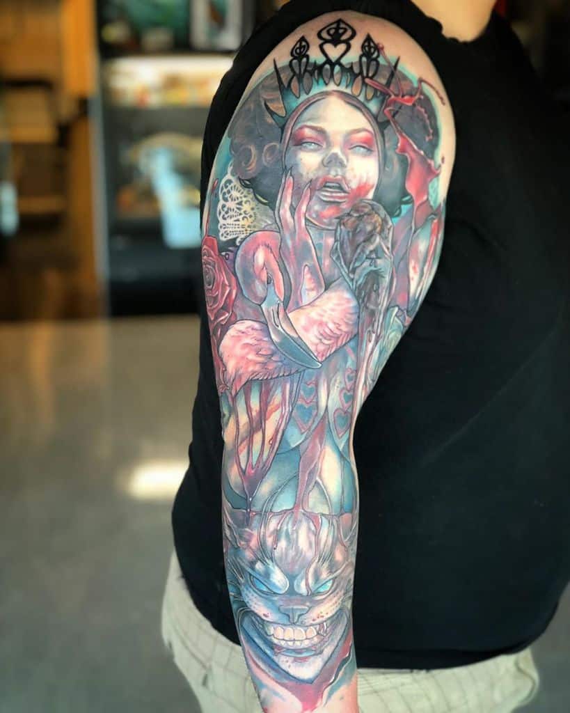 A vibrant, detailed tattoo featuring the Queen of Hearts, flamingos, roses, and the Cheshire Cat from Alice in Wonderland
