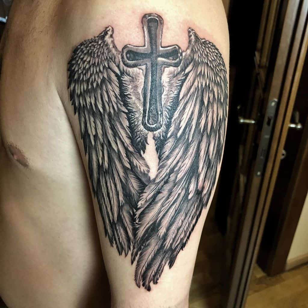 Intricate tattoo featuring large angel wings with a cross in the center, symbolizing faith, protection, and spirituality