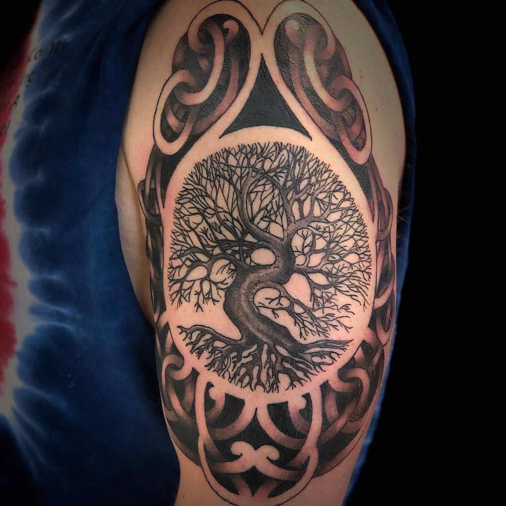 Intricate tree of life tattoo with detailed roots and branches, framed by bold tribal patterns on the upper arm