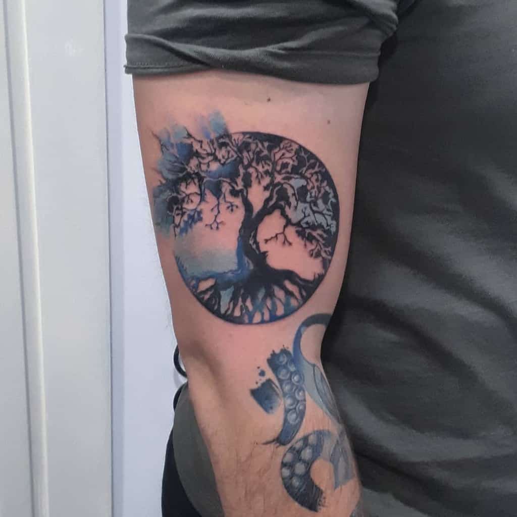 Tree of life tattoo with roots and branches forming a circle, enhanced by soft watercolor shades of blue and pink