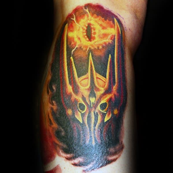Tattoo of a fiery helmet with the Eye of Sauron above, set against a dark background