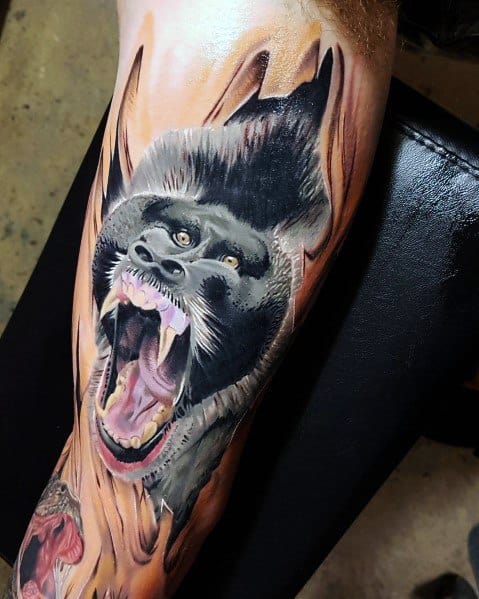 Realistic black and grey baboon tattoo with intense shading, fierce open-mouthed expression, and dynamic flames for a bold, powerful design.