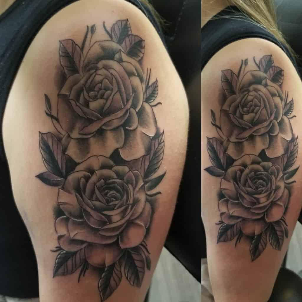 Tattoo of two shaded roses with leaves on an upper arm