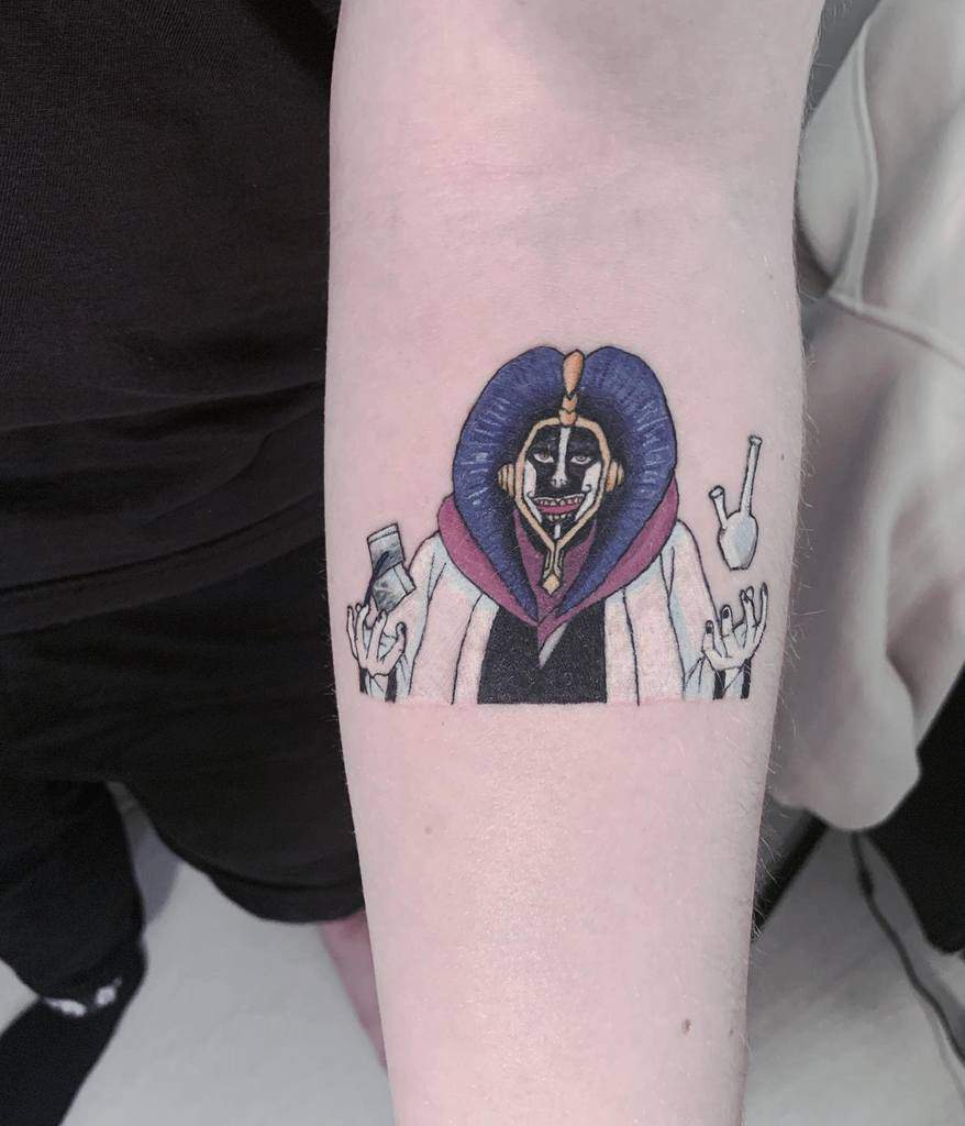 Colorful tattoo of Mayuri Kurotsuchi from Bleach, featuring his signature painted face, wide grin, and scientist tools 