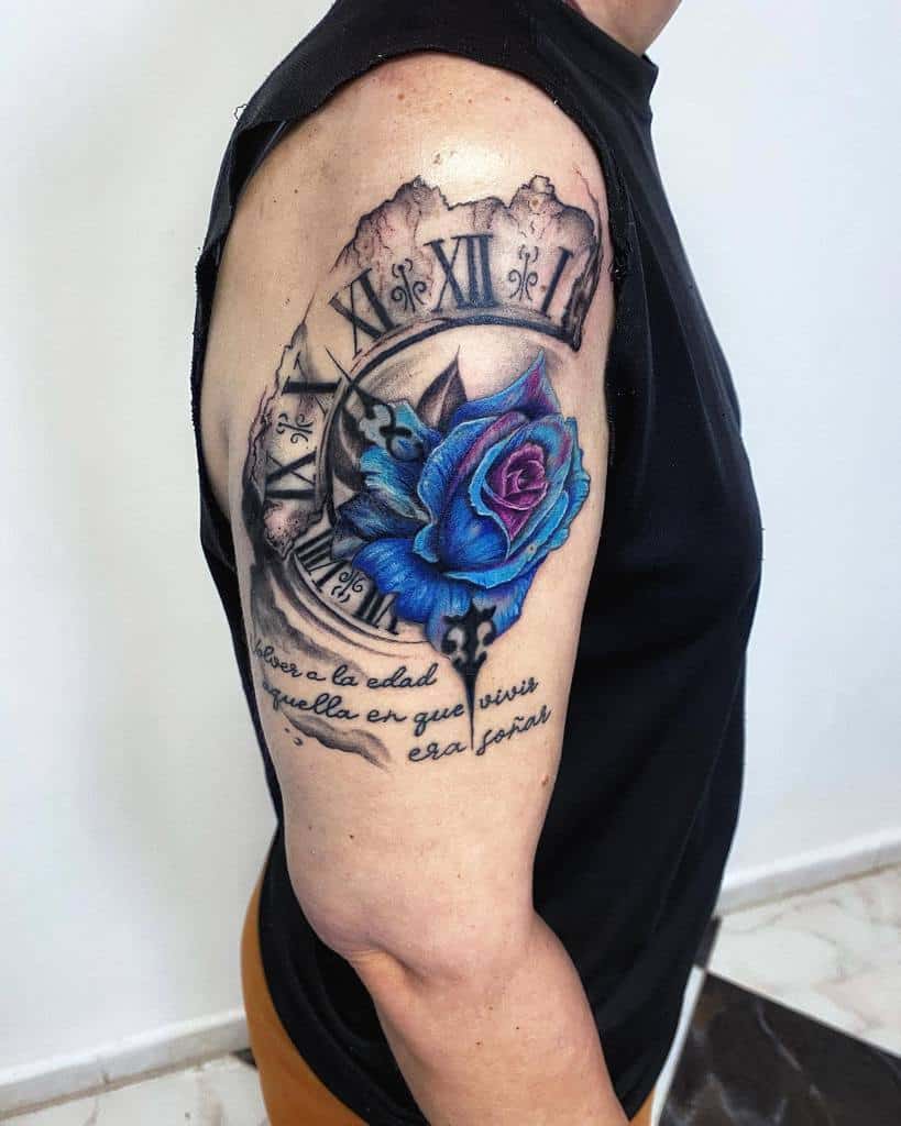 Tattoo of an intricate clock entwined with a vibrant blue rose on a man's upper arm, accentuated by elegant Spanish text
