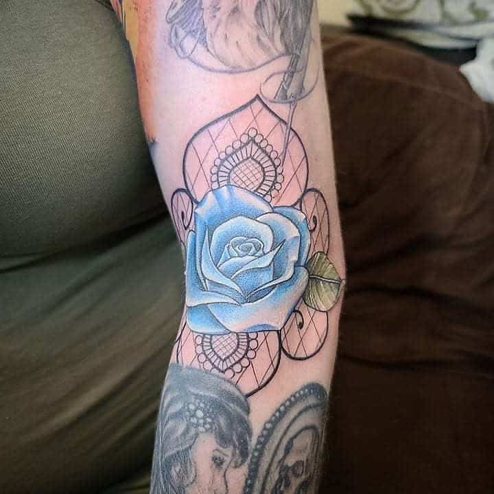 A stunning blue rose tattoo blooms with intricate geometric patterns on a person's arm, blending elegance and artistry seamlessly