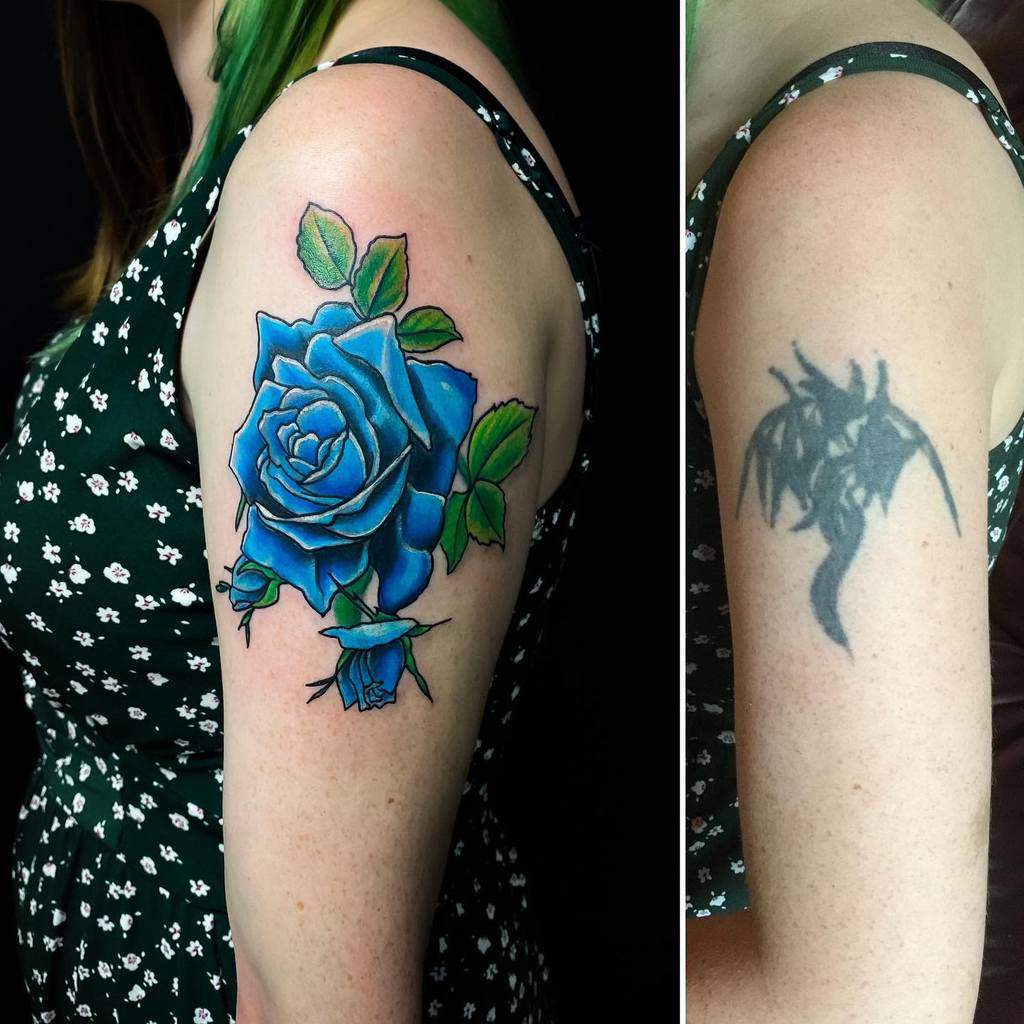 Colorful blue rose tattoo cover-up on a woman's upper arm, replacing a faded design