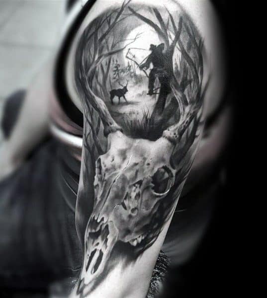Black and gray deer skull tattoo with a forest scene above, featuring a bowhunter aiming at a deer in the background.