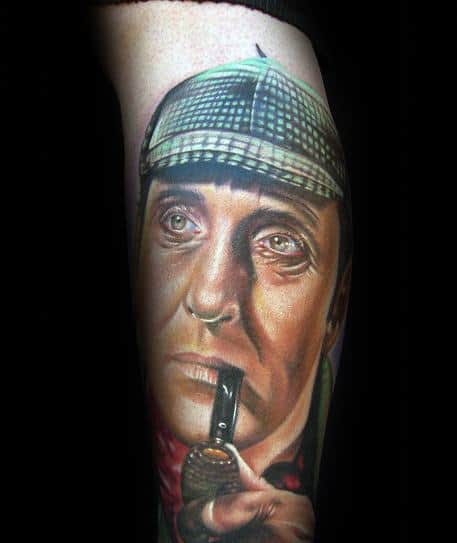 A tattoo of Sherlock Holmes wearing a checkered hat, pipe at his lips, and a contemplative expression