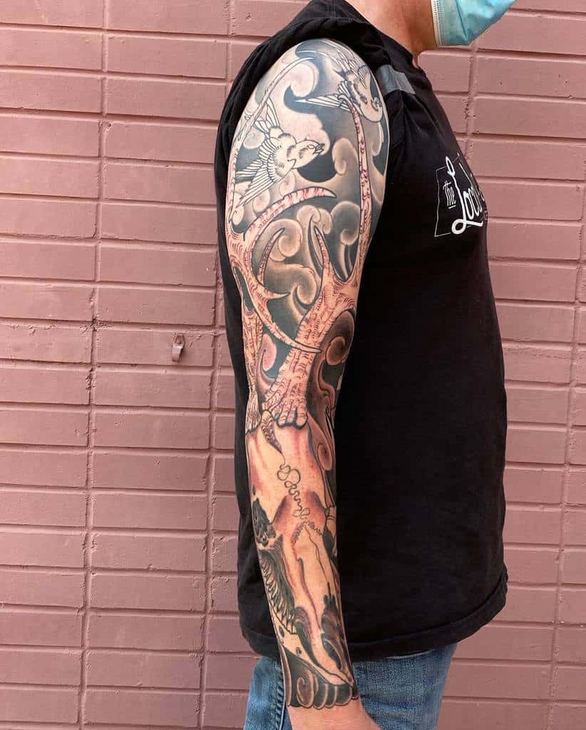 Detailed full-sleeve tattoo featuring a deer skull
