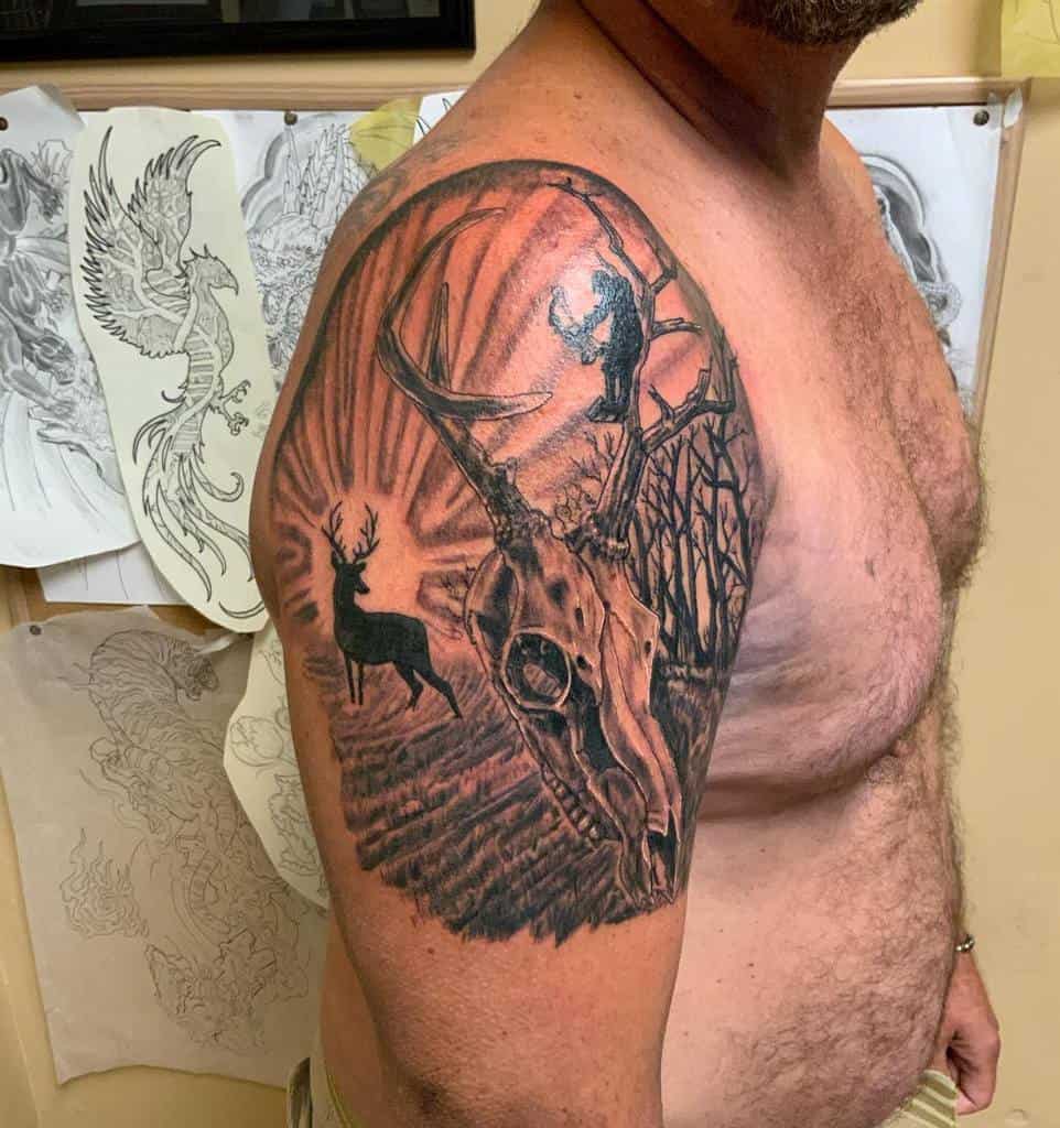 Man with a detailed deer-themed tattoo featuring a stag and a deer skull on his upper arm