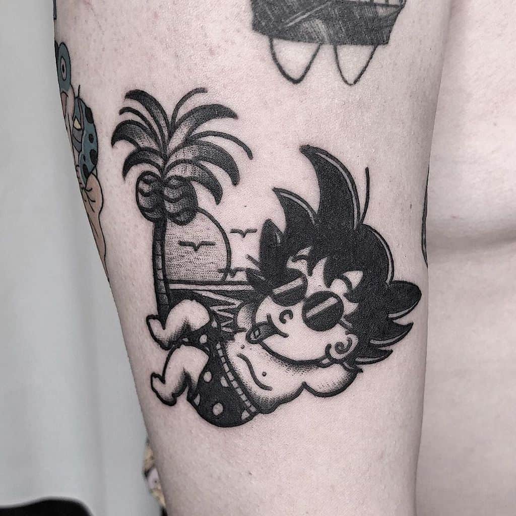 A black and white tattoo of young Goku from Dragon Ball, wearing swim trunks and sunglasses, lounging under a palm tree with a playful expression.