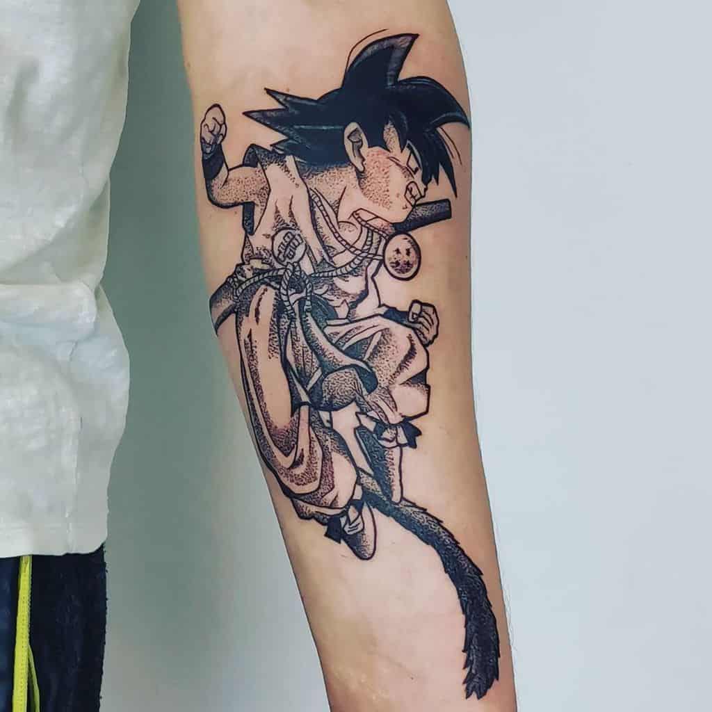 A tattoo of young Goku from Dragon Ball, mid-air with a clenched fist and his tail, holding a Dragon Ball, in black and white with dotted shading.