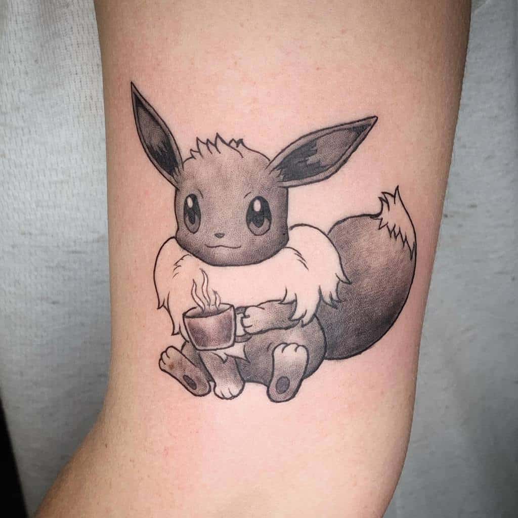 Cozy black and grey Eevee tattoo holding a steaming cup, radiating warmth and a relaxed, peaceful vibe