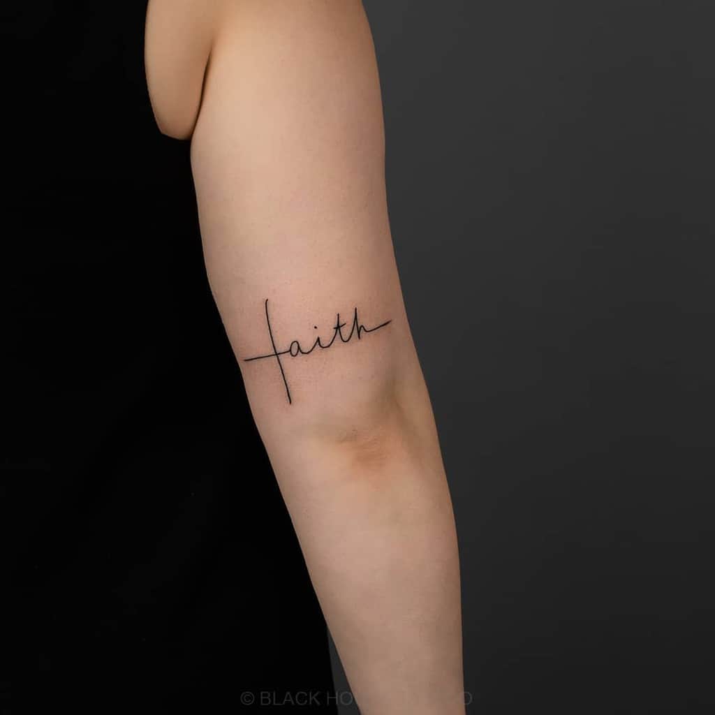 Tattoo of the word "faith" on a person's arm in a minimalist black script