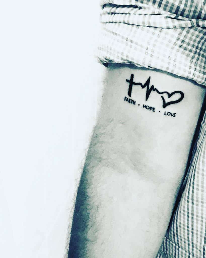Arm tattoo showcasing a heartbeat line intertwined with a heart, beautifully inked in black, with the inspiring words "Faith, Hope, Love" seamlessly integrated into the design, exuding a sense of harmony and strength