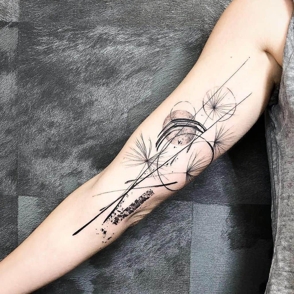 This tattoo features a modern, abstract design with dandelion elements and dynamic lines. It combines minimalist shapes with flowing details, symbolizing freedom and transformation.