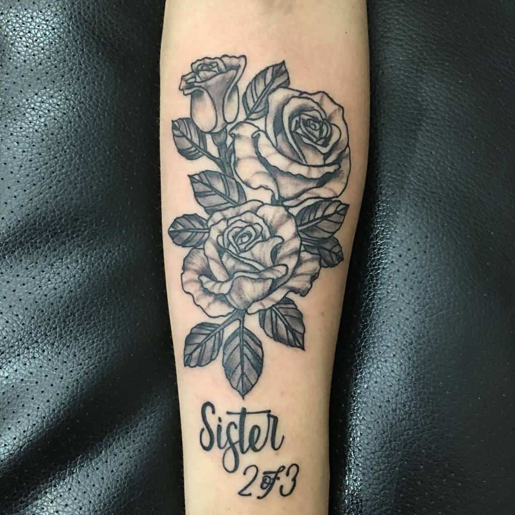 Black and grey tattoo featuring detailed roses with the text 'Sister 2 of 3,' symbolizing sibling bond and family connection