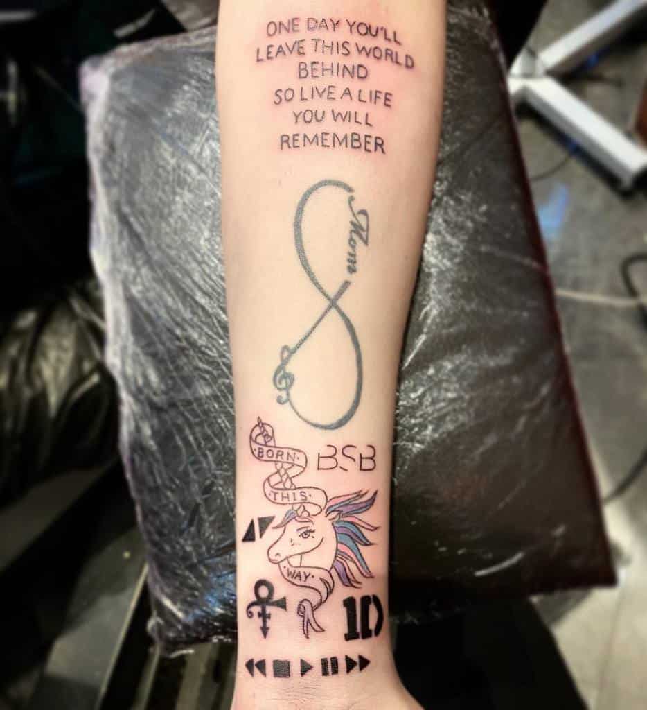 Tattoo featuring an inspirational quote, infinity music symbol, 'Born This Way' ribbon, unicorn, and various symbolic designs