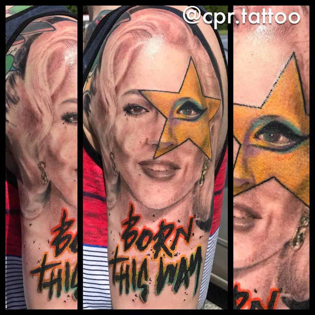 Tattoo of Lady Gaga's portrait with a golden star eye detail and 'Born This Way' text in bold orange and black graffiti style