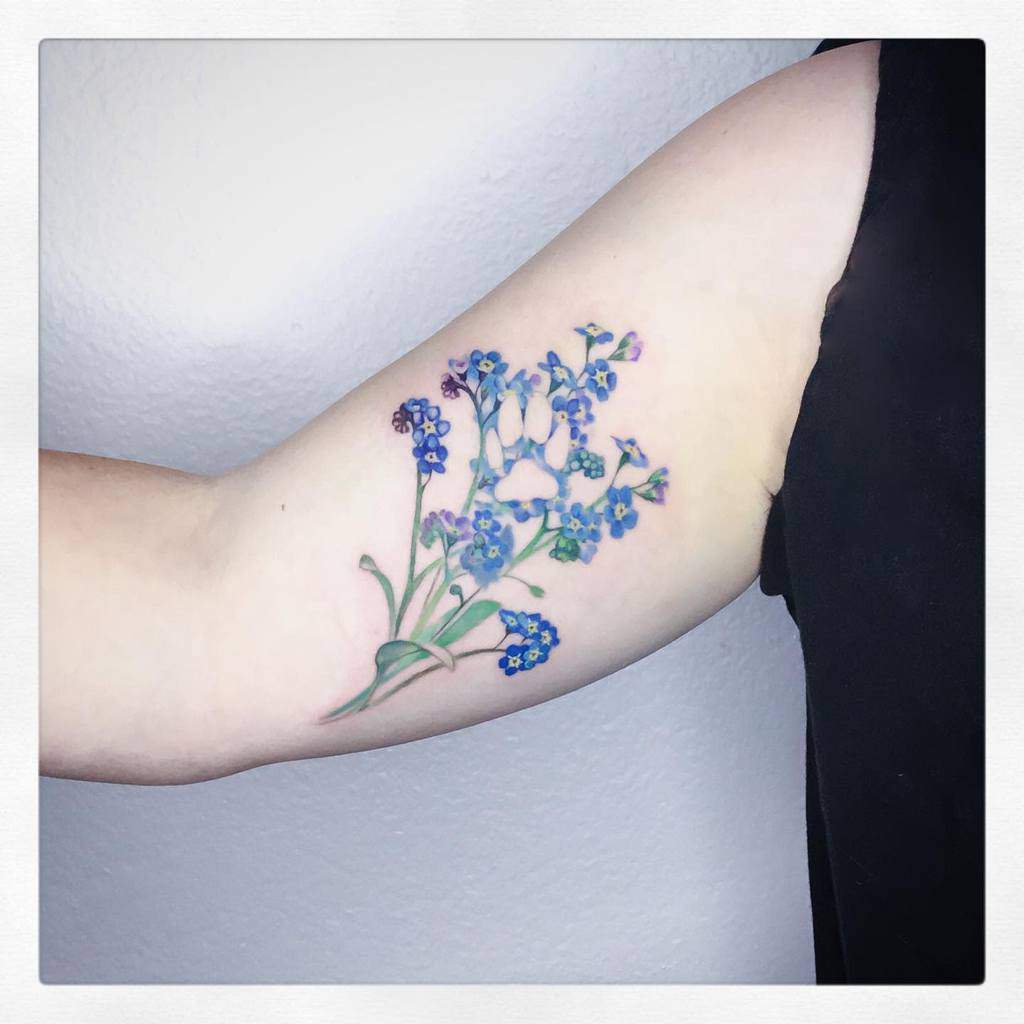 Forearm tattoo of forget-me-not blue flowers on light skin