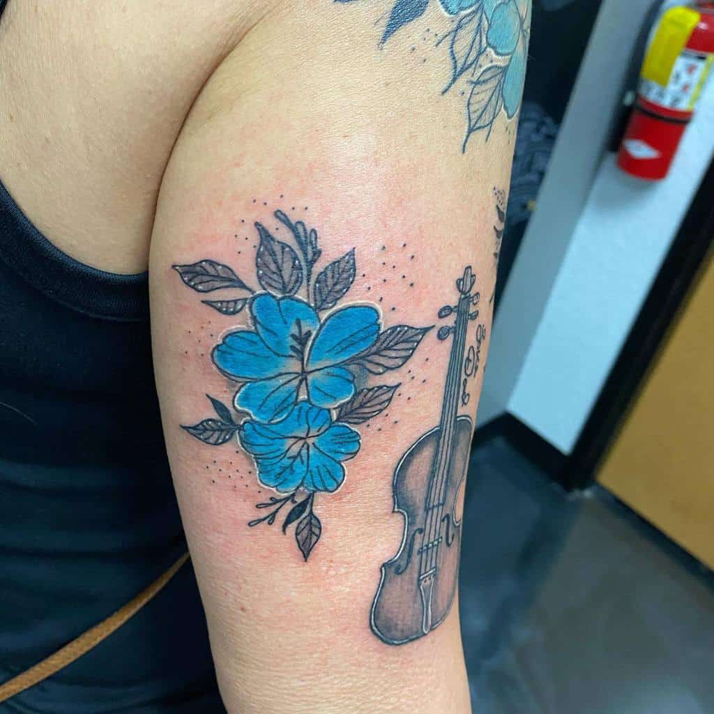 A tattoo of delicate blue forget-me-nots intertwined with a violin graces the upper arm