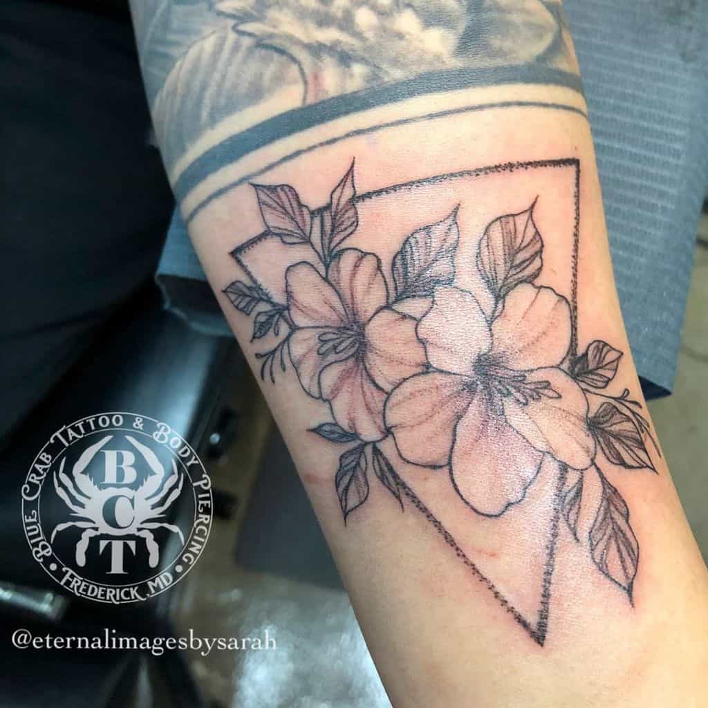 Black and gray floral tattoo within a triangle on an arm