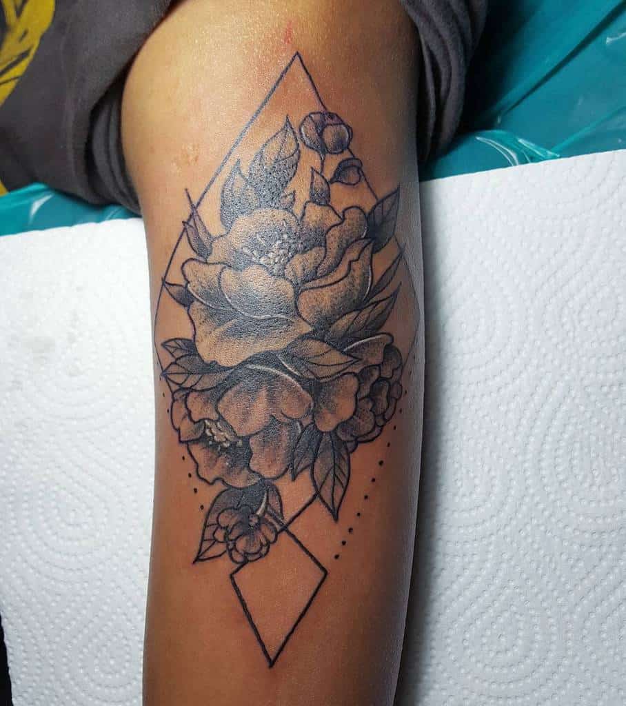 Black and white floral tattoo with geometric lines on a person's arm