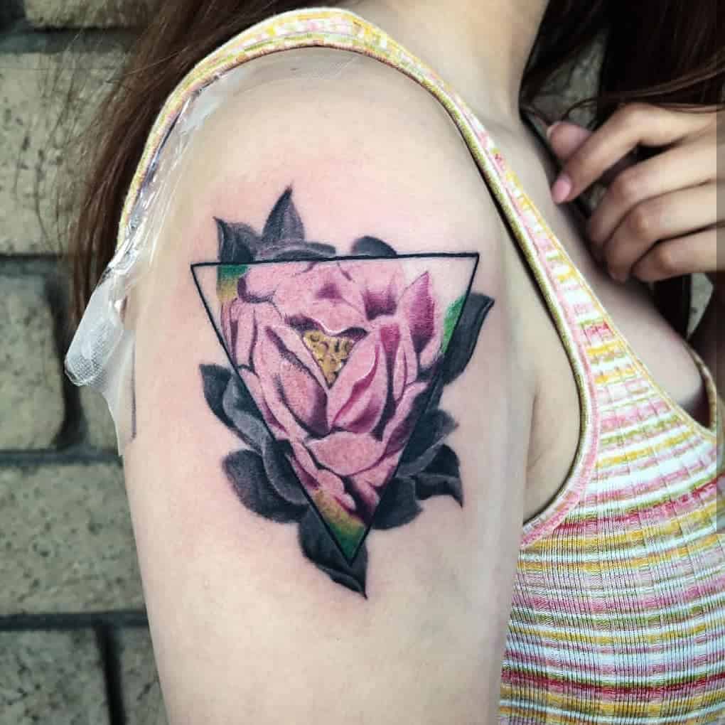 Floral tattoo with a triangle outline on a woman's upper arm, featuring a pink rose and green leaves