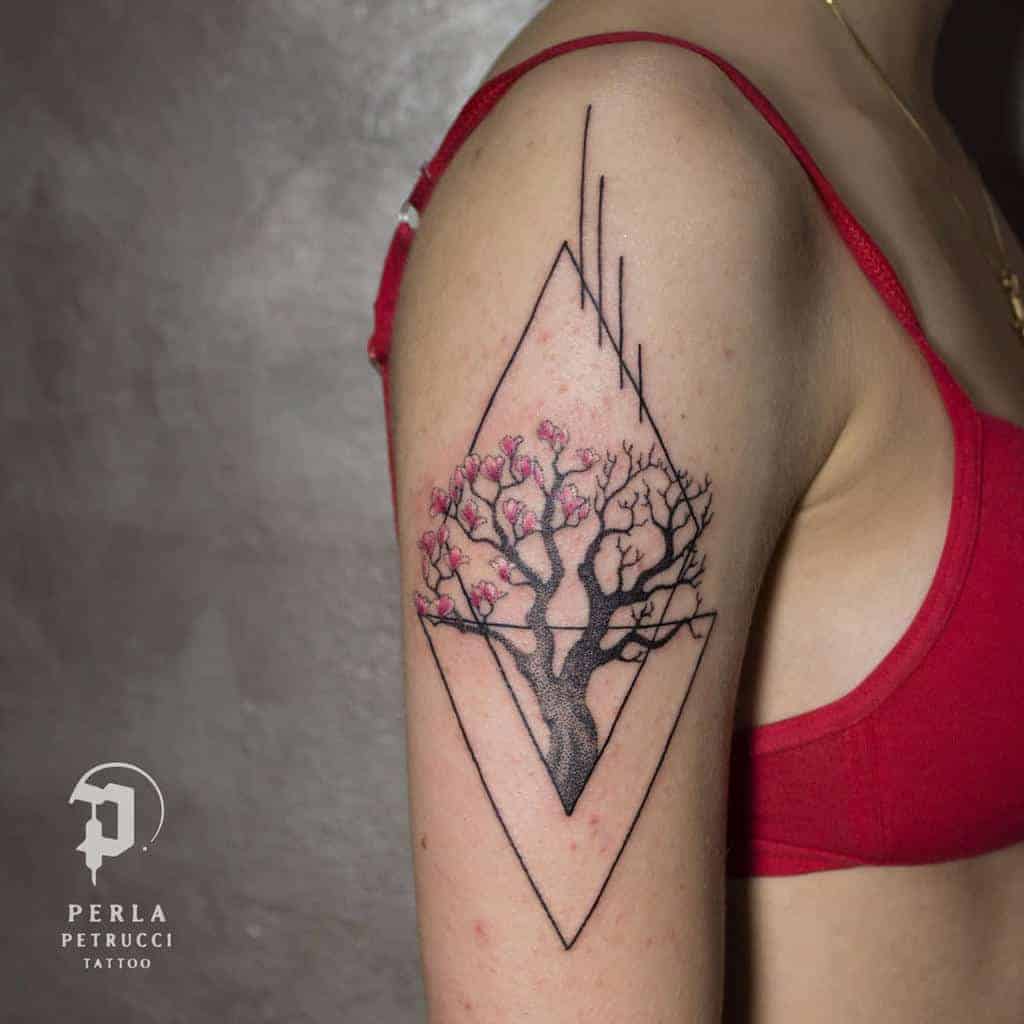 Geometric tree tattoo with pink blossoms on a person's upper arm
