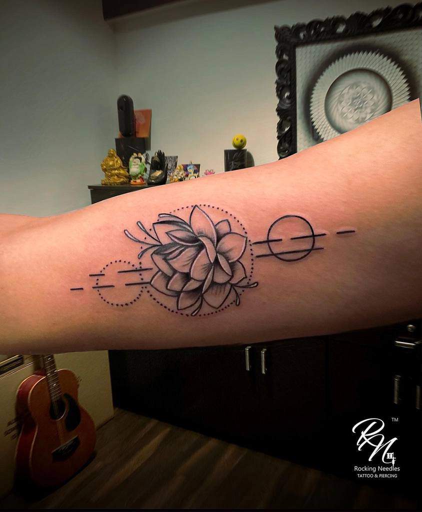Tattoo of a geometric lotus on an arm, featuring circles and dotted lines