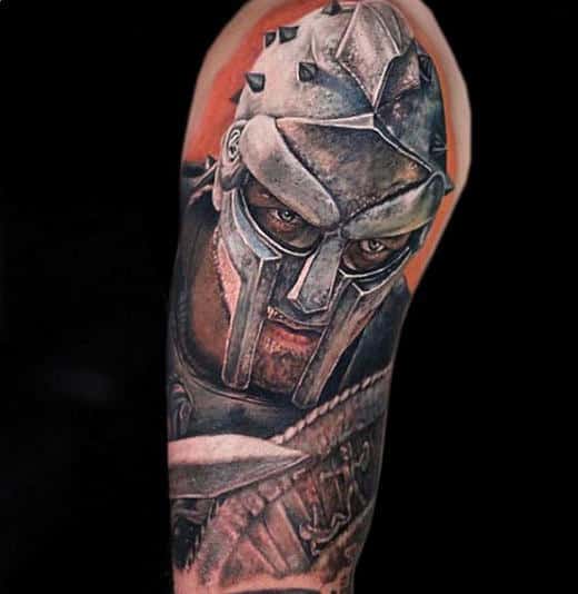 Arm tattoo of a gladiator wearing a spiked metallic battle helmet with an intense expression