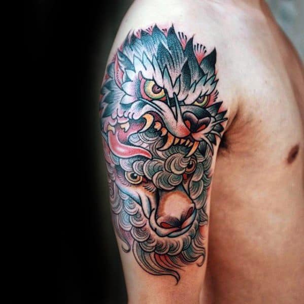 A detailed tattoo of a fierce wolf with colorful fur covering a person's upper arm