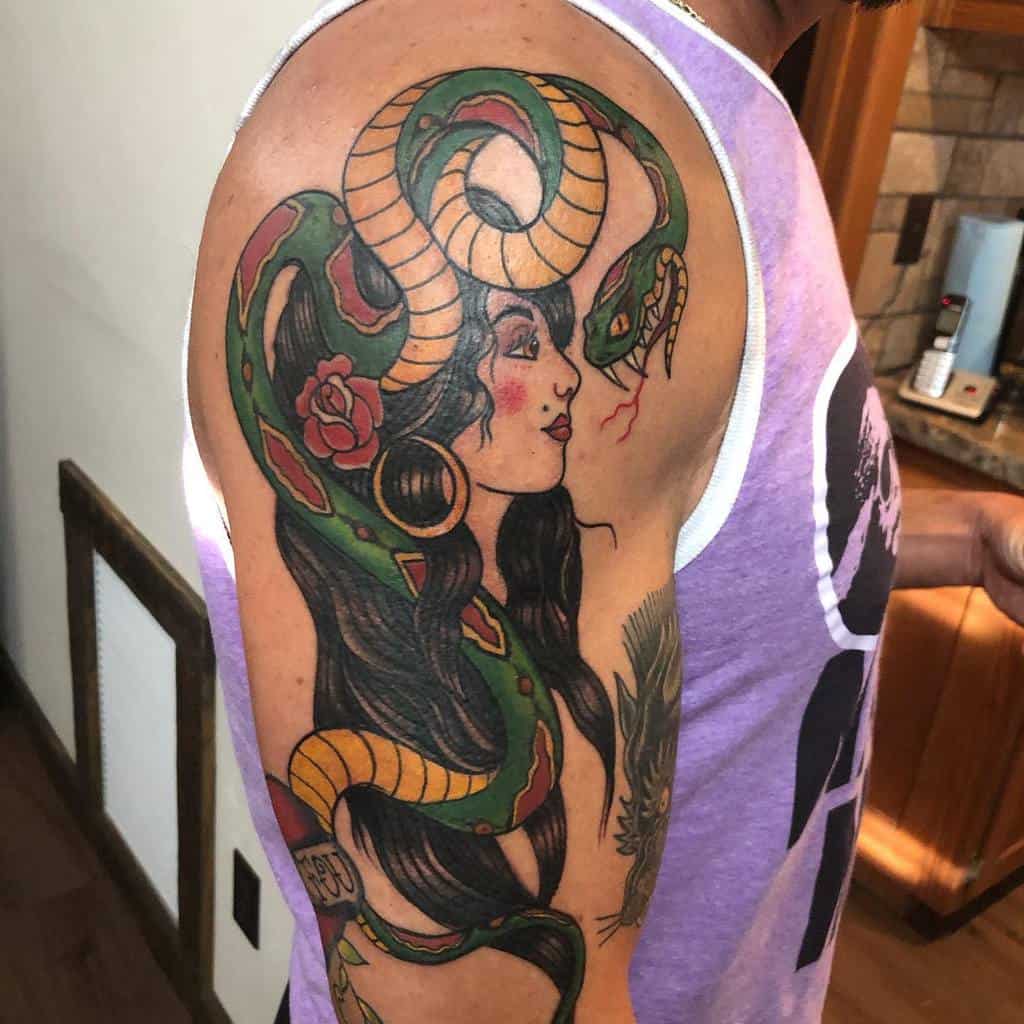 Tattoo of a gypsy woman with long hair and a green snake winding around her on a man's upper arm