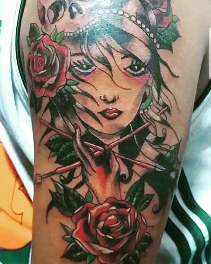 Tattoo of a geisha with roses and chopsticks on an upper arm