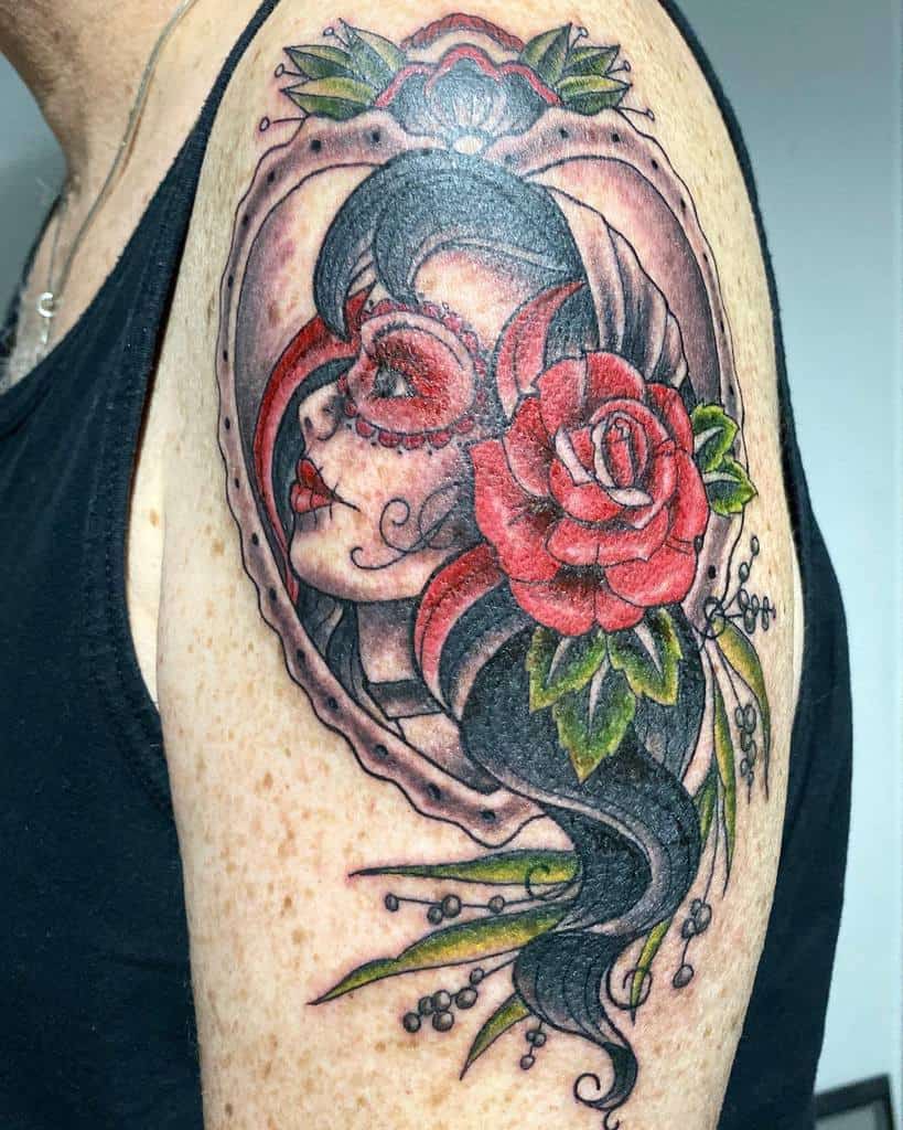 Tattoo of a gypsy woman with a rose and Day of the Dead face paint on an upper arm