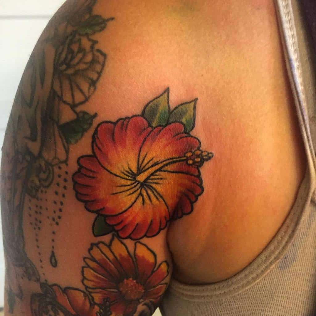 Upper arm tattoo featuring a vibrant orange and red hibiscus flower with green leaves, adding a tropical feel