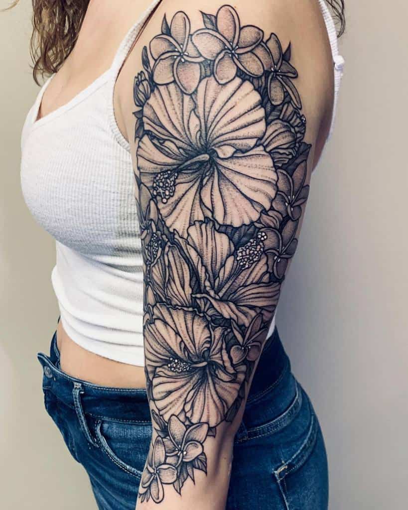 Full sleeve tattoo featuring intricate black and grey hibiscus and plumeria flowers with detailed leaves, creating a lush floral design