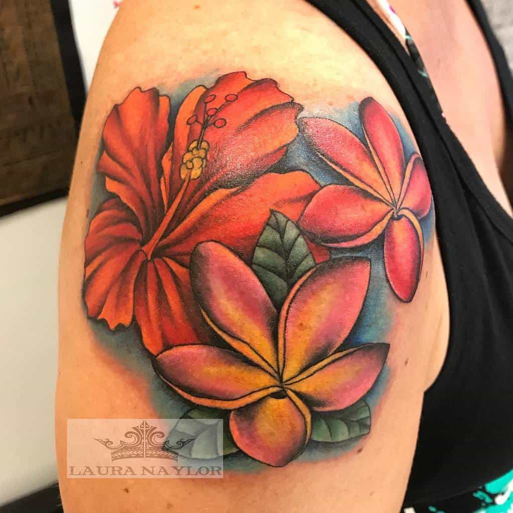 Upper arm tattoo featuring a vibrant red hibiscus and a colorful pink and yellow plumeria flower with green leaves