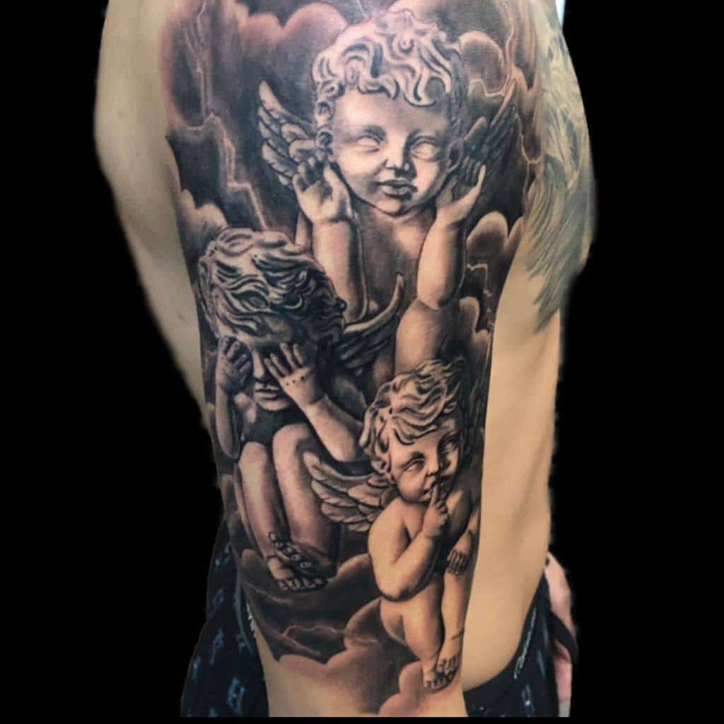 Tattoo of three cherubs on an arm, with one covering its ears, another its eyes, and the last its mouth